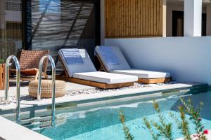 a swimming pool with two lounge chairs next to a house at Acacia - Explore your senses in Preveza