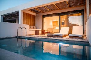 a swimming pool with white chairs and a house at Acacia - Explore your senses in Preveza