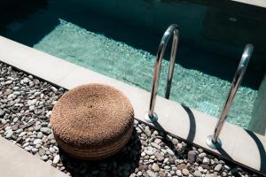 a straw hat sitting next to a swimming pool at Acacia - Explore your senses in Preveza