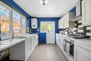 a large kitchen with blue walls and white cabinets at Spacious Luxury Garden House Free Parking in Bristol