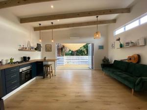 a living room with a green couch and a kitchen at Tree House by the Ocean in Kommetjie