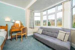 a bedroom with a couch and a desk and windows at Tyn-y-Coed Inn in Betws-y-coed