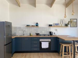 a kitchen with blue cabinets and a wooden table at Tree House by the Ocean in Kommetjie