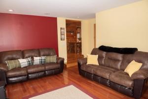 sala de estar con sofá de cuero y silla en The Whimsical Chalet chalet, en Mount Holly
