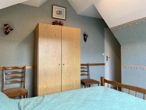ein Schlafzimmer mit einem Holzschrank und 2 Stühlen in der Unterkunft 539 - Maison 5 personnes en plein cœur d'Erquy. in Erquy