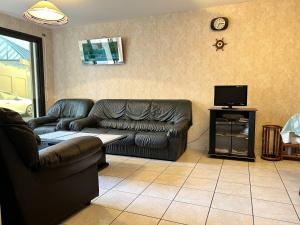 ein Wohnzimmer mit einem Ledersofa und einem TV in der Unterkunft 539 - Maison 5 personnes en plein cœur d'Erquy. in Erquy