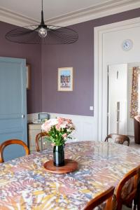 einen Esstisch mit einer Blumenvase darauf in der Unterkunft Villa Zachee - maison familiale & parking gratuit in Le Tréport