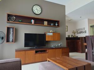 a living room with a tv and a clock on the wall at Miranda 514B 2br at Pico de Loro by Raquel's Place in Nasugbu