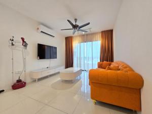 sala de estar con sofá naranja y TV de pantalla plana en Manhattan Condominium - Jalan Pasir Puteh - Ipoh, en Kampong Pinji