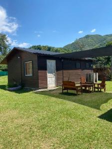 a log cabin with two benches in front of it at Complejo de Cabañas Ohana Salta in Campo Quijano