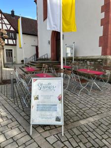 un cartel con sillas, mesas y una bandera en Streng's Weinstube, en Sommerach