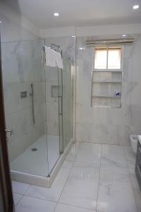 a white bathroom with a shower and a sink at House 24 in Abuja