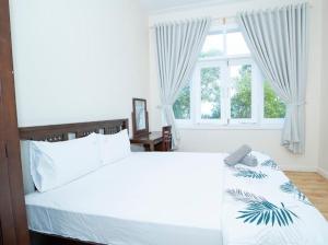 Un dormitorio con una gran cama blanca y una ventana en The Sealinks City Mũi Né - VILLA 5PN, en Ấp Ngọc Hải
