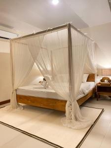 a bedroom with a canopy bed with mosquito netting at JOSEPHA COTTAGE in Ngurblut