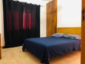 1 dormitorio con cama y cortina negra en Get house kira, en Cidade Velha