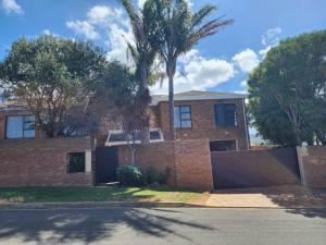 a brick house with a fence and palm trees at Little Greece in Cape Town