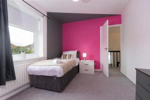 ein Schlafzimmer mit einer rosa Wand mit einem Bett und einem Fenster in der Unterkunft Park House in Durham