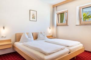 um quarto com uma cama grande e lençóis brancos em Haus Rosengarten Apt A em Terlano