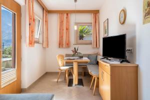 um quarto com uma secretária, uma televisão e uma mesa em Haus Rosengarten Apt A em Terlano