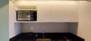 a kitchen with a microwave in a white cabinet at COSTE0104 - Premium Stella Maris in Salvador