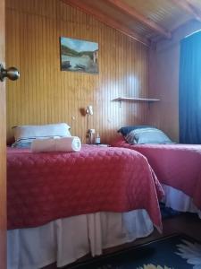 two beds in a hotel room with red sheets at Hospedaje Familiar Doña Juanita in Puerto Montt