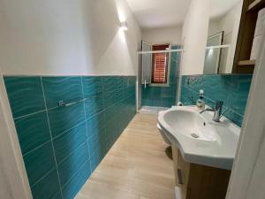 a bathroom with a white sink and a green tiled wall at Case vacanze Spagnola 106 in Marsala