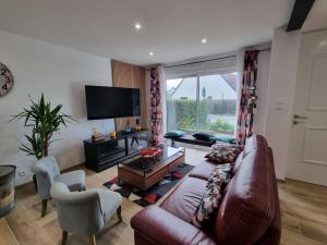 a living room with a brown leather couch and a tv at La Tanière de la baie - Maison 6-8 pers in Le Val-Saint-Père