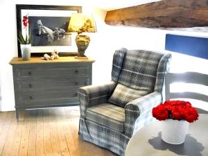 ein Wohnzimmer mit einem Stuhl und einem Tisch mit roten Blumen in der Unterkunft Villa de 3 chambres avec piscine privee jardin clos et wifi a Arsac in Arsac