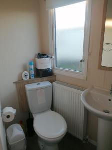 a bathroom with a toilet and a sink and a window at 4-Bedroom Caravan static home in Clacton-on-Sea in Clacton-on-Sea