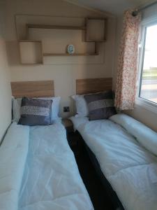 two beds sitting in a room with a window at 4-Bedroom Caravan static home in Clacton-on-Sea in Clacton-on-Sea