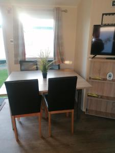 a dining room table with two chairs and a television at 4-Bedroom Caravan static home in Clacton-on-Sea in Clacton-on-Sea