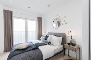 1 dormitorio con cama con espejo y ventana en Executive Luxury apartment in Vauxhall with balcony, en Londres
