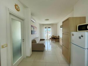 uma cozinha com um frigorífico e uma sala de estar em Appartamento Al Faro I TerraceRelax&Parking em Lignano Sabbiadoro