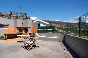 Un patio con una mesa y sillas en un tejado. en Mother's House, en Calheta