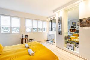 een groot geel bed in een kamer met ramen bij GuestReady - Modern Comfort in Vincennes in Vincennes