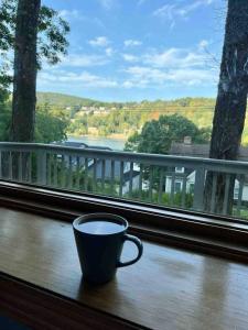une tasse de café assise sur un rebord de fenêtre avec vue dans l'établissement Candlewood Lake Retreat with year round views, à New Milford