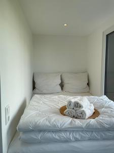 Una cama blanca con un montón de toallas. en Tinyhaus Supreme für 4 Personen, en Fuchsmühl
