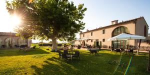 einen Garten mit Tischen und Stühlen und einem Baum und einem Gebäude in der Unterkunft Locanda Sant'Agata in San Giuliano Terme