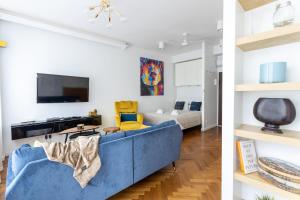 sala de estar con sofá azul y TV en Golden Apartments in Warsaw - City Center - Żurawia, en Varsovia
