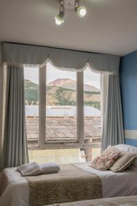 een slaapkamer met een bed en een groot raam bij Hotel Sol del Sur in Esquel
