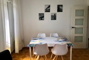mesa de comedor con 4 sillas blancas y pared blanca en Vivienda de Uso Turístico Cariño, en Cariño