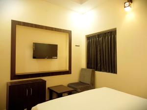 um quarto com uma cama, uma cadeira e um espelho em R Hotels By Suraj Residency Yercaud em Yercaud