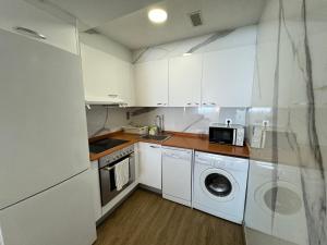 a kitchen with white cabinets and a washer and dryer at El pilar a 7 minutos in Zaragoza