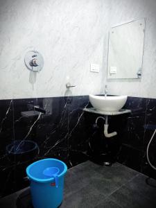 a bathroom with a sink and a mirror and a bucket at R Hotels By Suraj Residency Yercaud in Yercaud