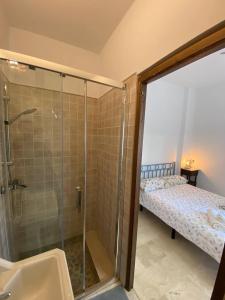 ein Badezimmer mit Dusche und Waschbecken und ein Bett in der Unterkunft Apartamento Crucero 2, la Jara in Sanlúcar de Barrameda