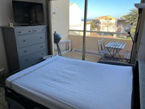 a bedroom with a bed and a tv and a balcony at Saint clair in Le Lavandou