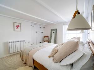 a white bedroom with a bed and a lamp at Bell Cottage in Saint Teath