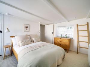 a white bedroom with a bed and a wooden dresser at Bell Cottage in Saint Teath +17 photos