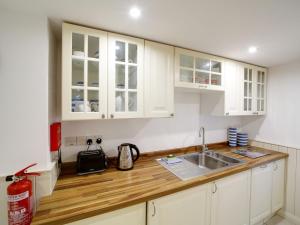 a kitchen with white cabinets and a wooden counter top at Bosuns Locker in Port Isaac