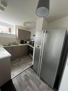 a kitchen with a stainless steel refrigerator and wooden floors at The M Rooms in Kirk of Shotts